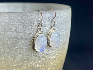 Simple and elegant, these oval rainbow moonstone earrings feature cabochon cut rainbow moonstones and are finished with detailed sterling silver surrounds and very generous shepherd hooks. Measurements: height 3.2 mm (0.13 in) including hook, width 1.3 cm