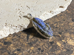 Hand carved labradorite pendant depicting Ganesh, elephant headed god of wisdom, prosperity and new beginnings. This is a unique piece, a smaller oval pendant that has a very attractive deep blue luminosity that comes alive depending on the angle of lighting. Sterling silver frame and bail. The bail is generous enough to allow a large chain or cord to pass through.  This unisex labradorite pendant will suit both men and women.  Measurements: height 4.6 cm including bail, width 1.7 cm