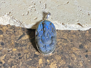 Hand carved labradorite pendant depicting Ganesh, elephant headed god of wisdom, prosperity and new beginnings. This is a unique and individual piece, a medium/large oval pendant that has a very attractive deep blue luminosity that comes alive depending on the angle of lighting. Sterling silver frame and bail. The bail is generous enough to allow a large chain or cord to pass through.  This unisex labradorite pendant will suit both men and women.  Measurements: height 5.3 cm including bail, width 2.6 cm