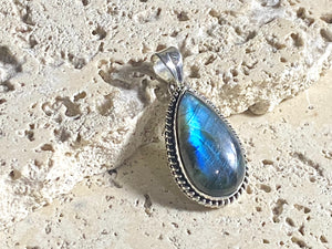 Lovely teardrop labradorite pendant set in twisted sterling silver surround with a generous bail to take a large chain or cord. A high set stone with excellent light blue colour and fire.  Measurements: Length including bail 4 cm, width at widest point 2 cm