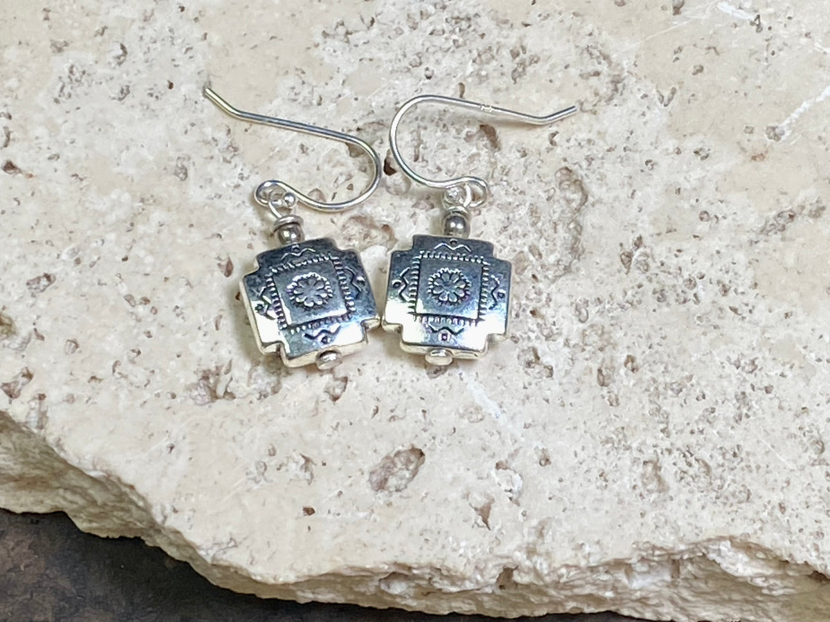Cross earrings with a southwest vibe. The body of the earring is made from a non-tarnishing white metal indistinguishable from silver, while the other parts and hooks are sterling silver. Lightweight and easy to wear, the pattern on the earring is repeated on both sides. Measurements: drop including hook 2.5 cm
