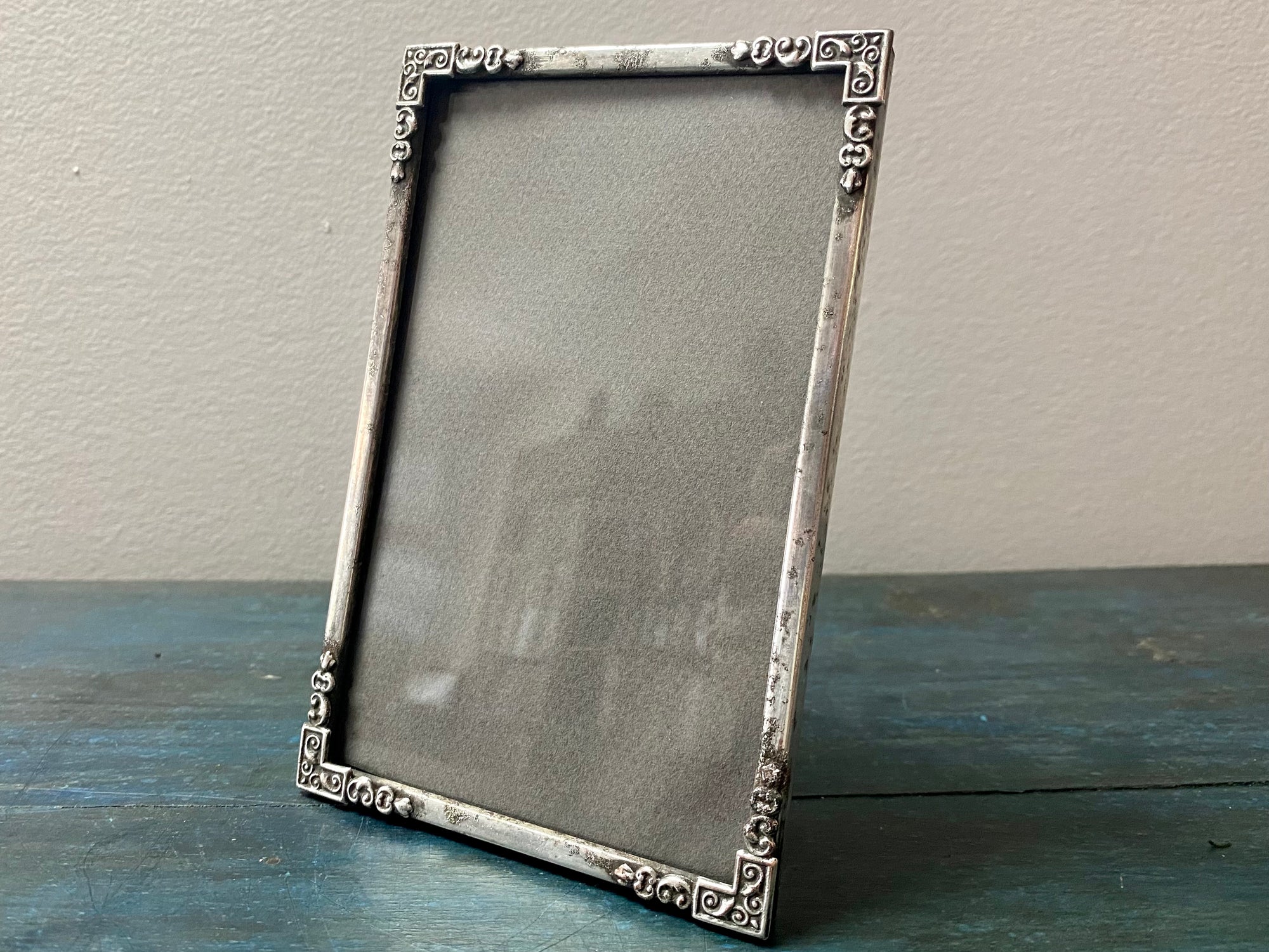 Full of character, this charming photo frame is silver plate over what appears to be an iron or brass base metal. While it it does show pitting and marking, its appearance is very much in keeping with its age. Circa 1920. Outside frame 14.5 x 9.2 cm, inside 8.2 x 18 cm.
