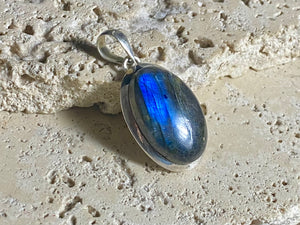 Elegant oval labradorite pendant set in sterling silver with a generous bail to take a large chain or cord. A high set stone with excellent blue colour and fire.  Measurements: Length including bail 4 cm, width at widest point 2 cm