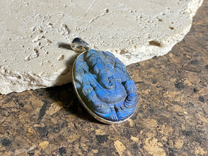 Hand carved labradorite pendant depicting Ganesh, elephant headed god of wisdom, prosperity and new beginnings. This is a unique and individual piece, with a deep blue luminosity enhanced by the depth of the stone, that changes depending on the angle of lighting. Sterling silver frame and bail. The bail is generous enough to allow a large chain or cord to pass through.  This unisex labradorite pendant will suit both men and women.  Measurements: height 5.2 cm including bail, width 3 cm