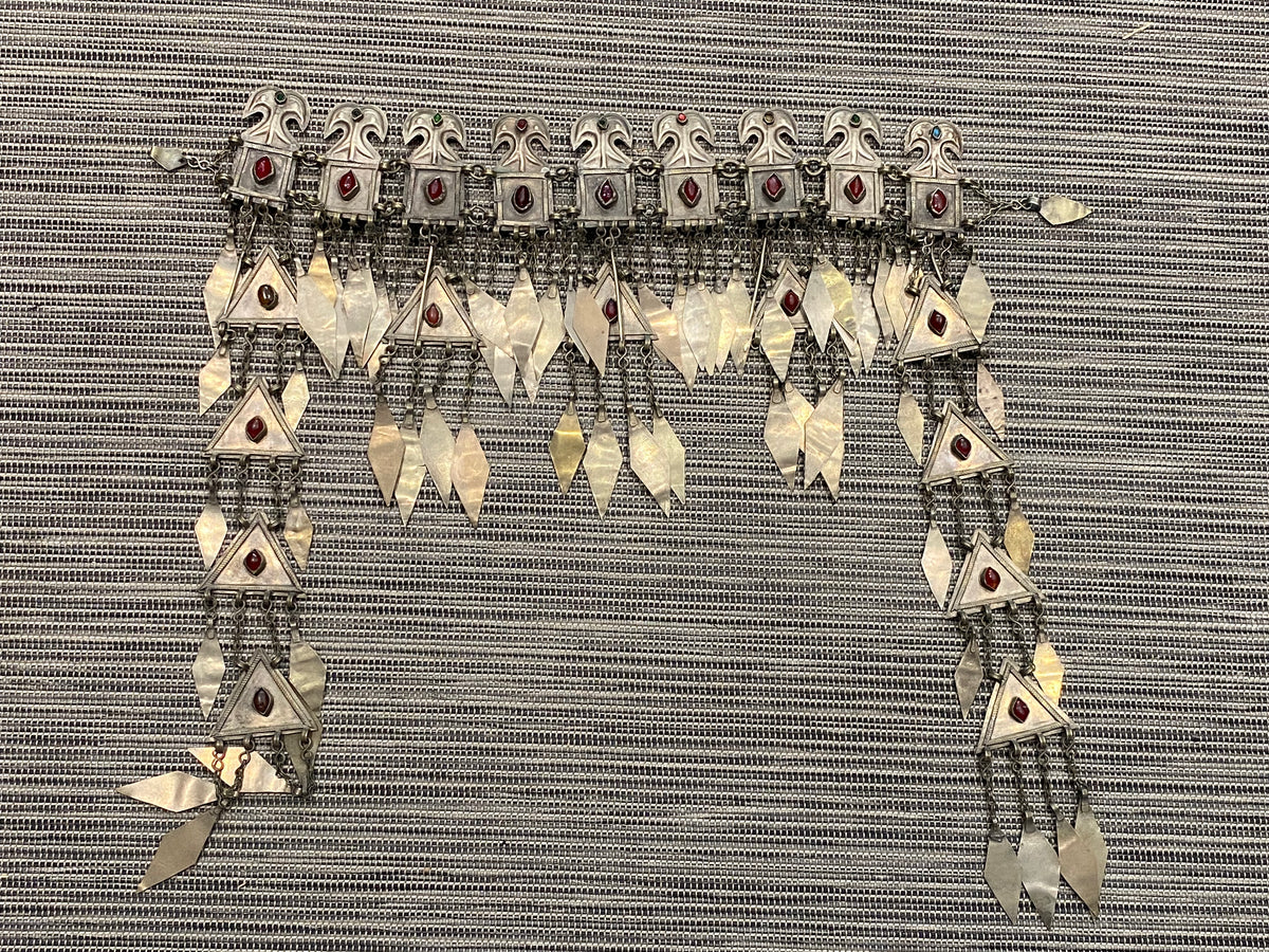 Ersari headdress consisting of a metal gaashbaagh & a high embroidered conical hat into which it attached with long spikes. The cap is quilted cotton covered in velvet and detailed silk embroidery. An heirloom piece, dating from 1870-1890. Cap height 23 cm. Tiara: width 53 cm, height of band 7 cm, side dangles 44 cm