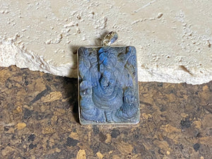 Hand carved large square labradorite pendant depicting Ganesh, elephant headed god of wisdom, prosperity and new beginnings. This is a unique and individual piece, hand carved by an artisan in Jaipur, with a light blue luminosity that changes depending on the angle of lighting. Sterling silver frame and bail. The bail is generous enough to allow a large chain or cord to pass through.  This unisex labradorite pendant will suit both men and women.  Measurements: height 5.2 cm including bail, width 3 cm