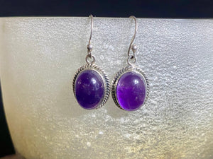 Amethyst earrings featuring high quality stones, classic darker cabochon amethysts with a detailed oval bezel. Sterling silver hook and mounts. Our amethyst earrings are open at the back to allow the natural light of the amethysts to shine through. Size 3.2 cm length including hook.