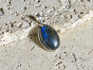 Elegant oval labradorite pendant set in sterling silver with a generous bail to take a large chain or cord. A high set stone with excellent blue colour and fire.  Measurements: Length including bail 4 cm, width at widest point 2 cm