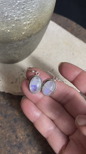 Simple and elegant, these oval rainbow moonstone earrings feature cabochon cut rainbow moonstones and are finished with detailed sterling silver surrounds and very generous shepherd hooks. Measurements: height 3.2 mm (0.13 in) including hook, width 1.3 cm