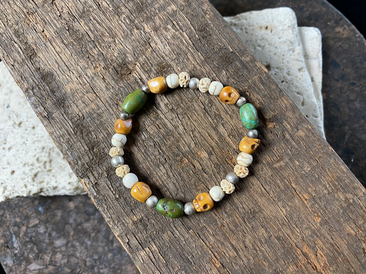 Stretchy bracelet featuring hand carved yak bone skulls, natural antique Tibetan turquoise, undyed howlite , carved lotus root and sterling silver beads. Designed to fit on a wrist 11-14 cm circumference 