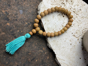 29-bead wrist mala made from genuine sandalwood beads with turquoise blue cotton tassel. On elastic. This is a large mala bracelet