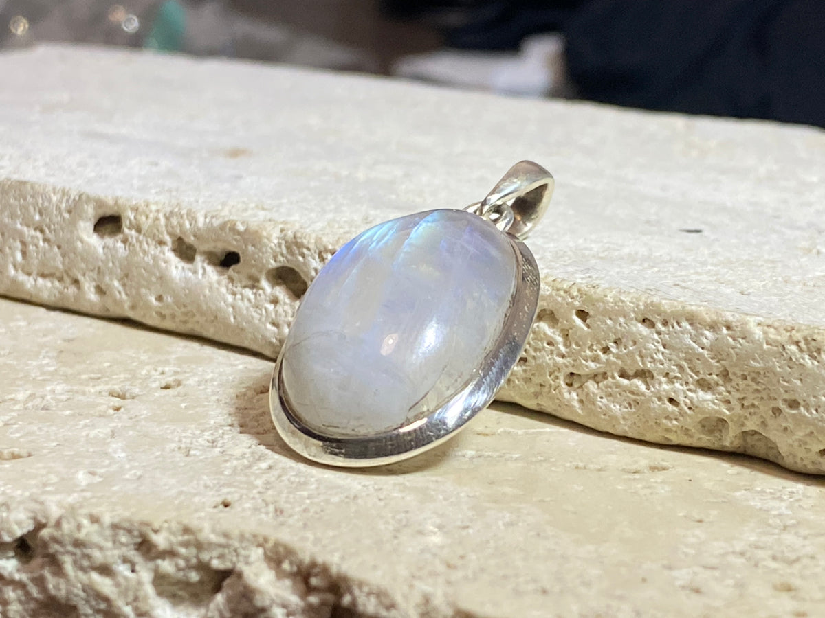 Oval high cut rainbow moonstone pendant set in sterling silver with a generous flexible bail to take a large chain or cord. A high quality stone with blue colour and fire. 