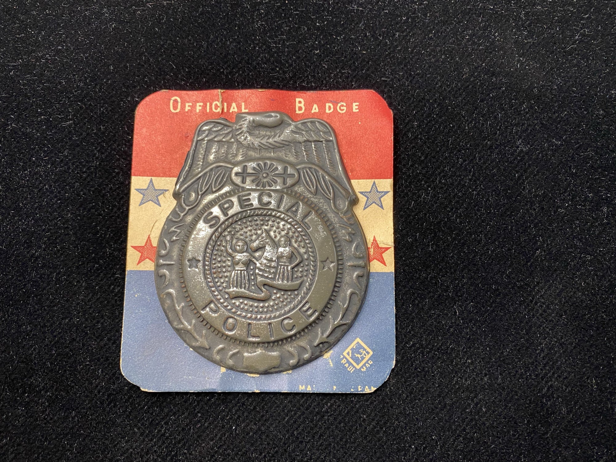 pressed tin novelty kid's police badge is still mounted on its original red white and blue display card. Made in Japan circa 1950