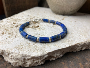 Lapis lazuli bracelet consists of hand cut tubes of dark blue natural matched,  graduated lapis tube beads. Finished with sterling silver ball spacer beads and a sterling silver clasp