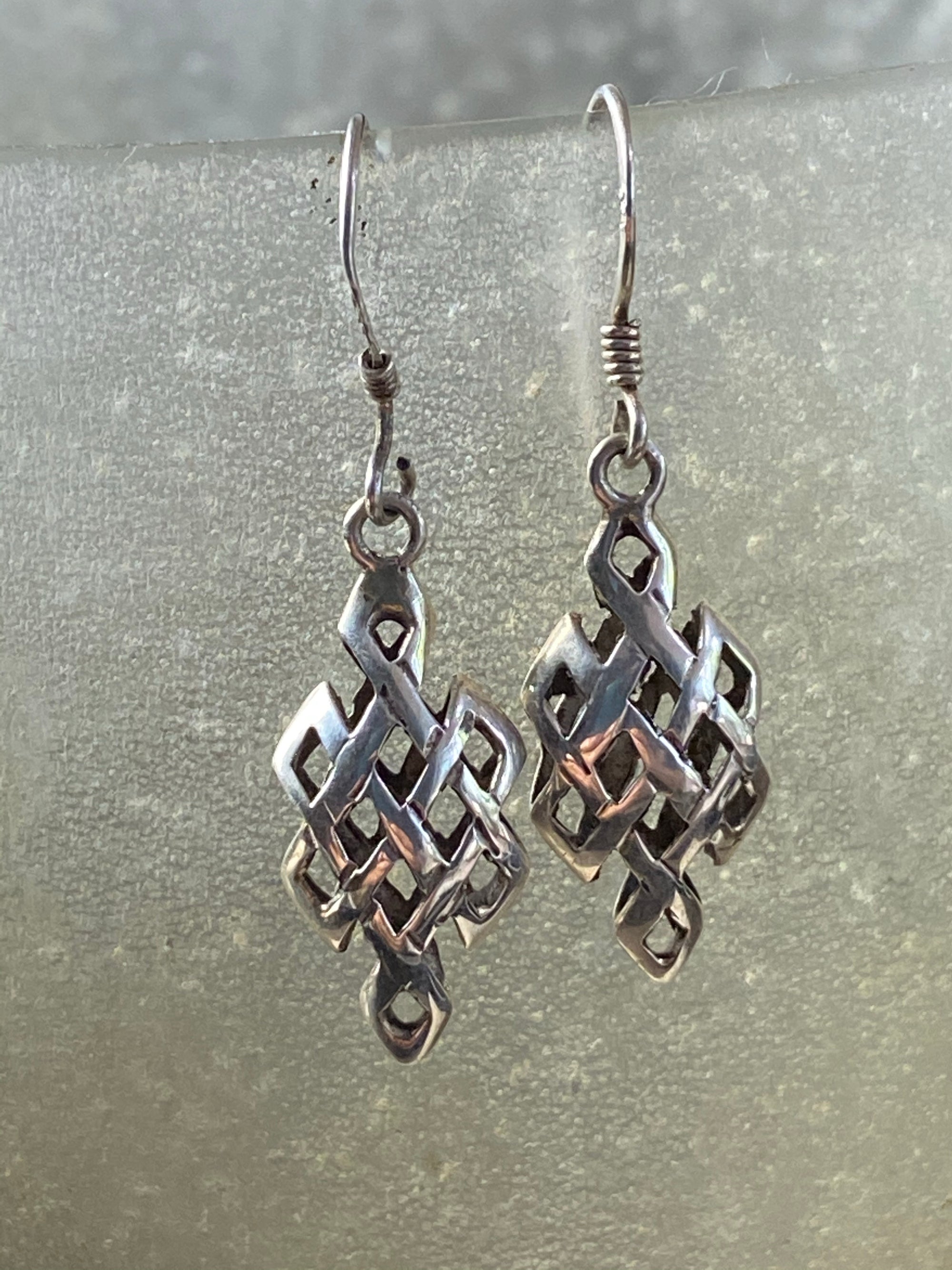 Sterling silver endless knot earrings featuring a 3 dimensional cutout endless knot