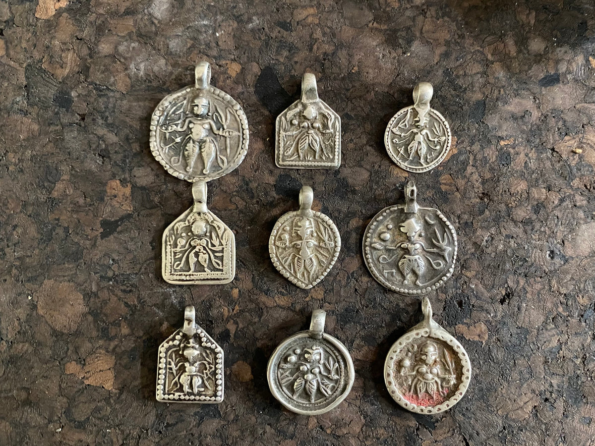 Antique silver amulets representing the Hindu god Kali, in her protective form, and dating from the early 19th - early 20th century.  Measurements: all vary between 1.5 and 2.2 cm in width