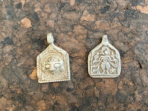 Antique silver amulets representing the Hindu god Shiva, traditionally worn for protection and good luck. Originating in southern India and dating from the late 19th century.