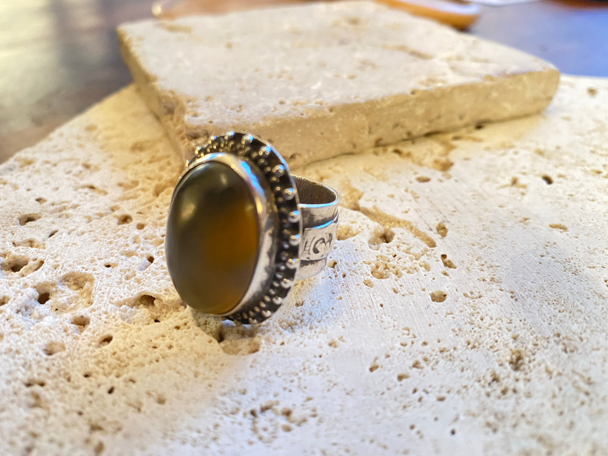 Afghan tribal ring features a large light coloured  cabochon carnelian stone.  The wide ring band features a stunning applied panel of work with a small crest panel for engraving. High grade silver. Late 19th century. Size 6.5