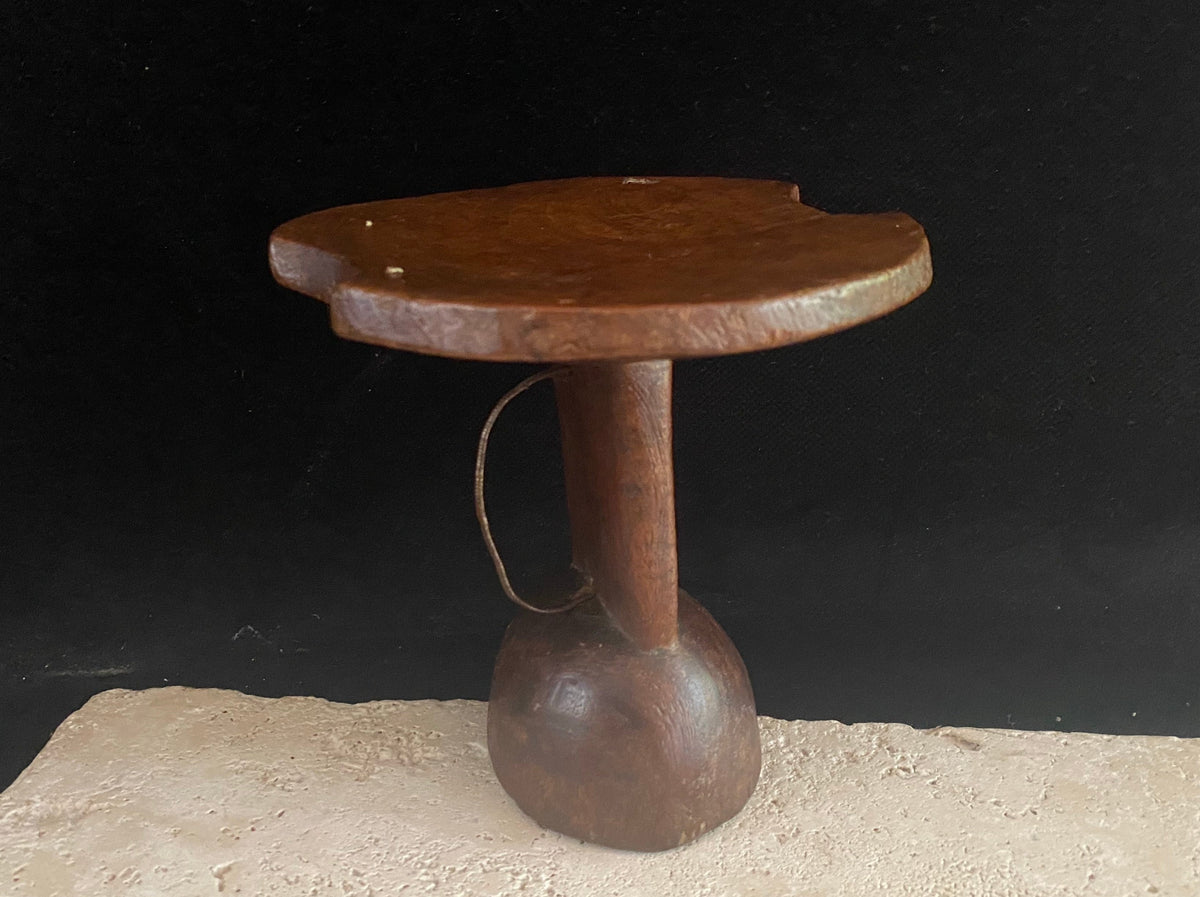 Mursi wood headrest, southern Ethiopia.   Carved from a single piece of wood, with cutouts. Vintage, late 20th century, with patina and wear appropriate to its age. A wire handle is attached. 15 cm height