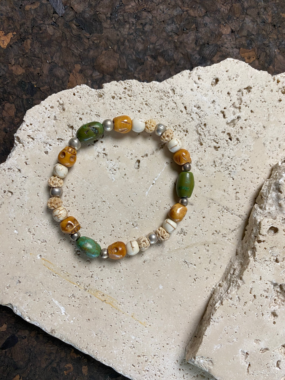 Stretchy bracelet featuring hand carved yak bone skulls, natural antique Tibetan turquoise, undyed howlite , carved lotus root and sterling silver beads. Designed to fit on a wrist 11-14 cm circumference 