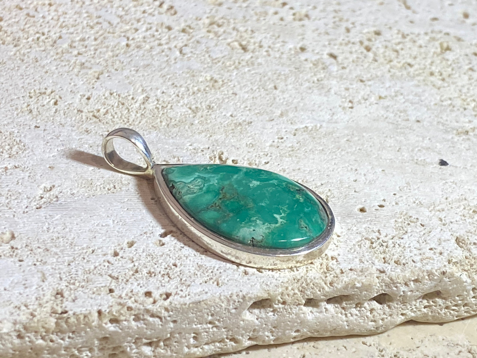 This strong green turquoise teardrop pendant is set off by a sterling silver bezel, topped by a bail that’s large enough to accommodate a thick chain or cord. Can be worn by men or women. A stunning piece of turquoise from Tibet. 