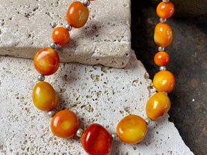 Bold coral necklace featuring orange red coral boulder beads of different sizes finished with sterling silver detailing