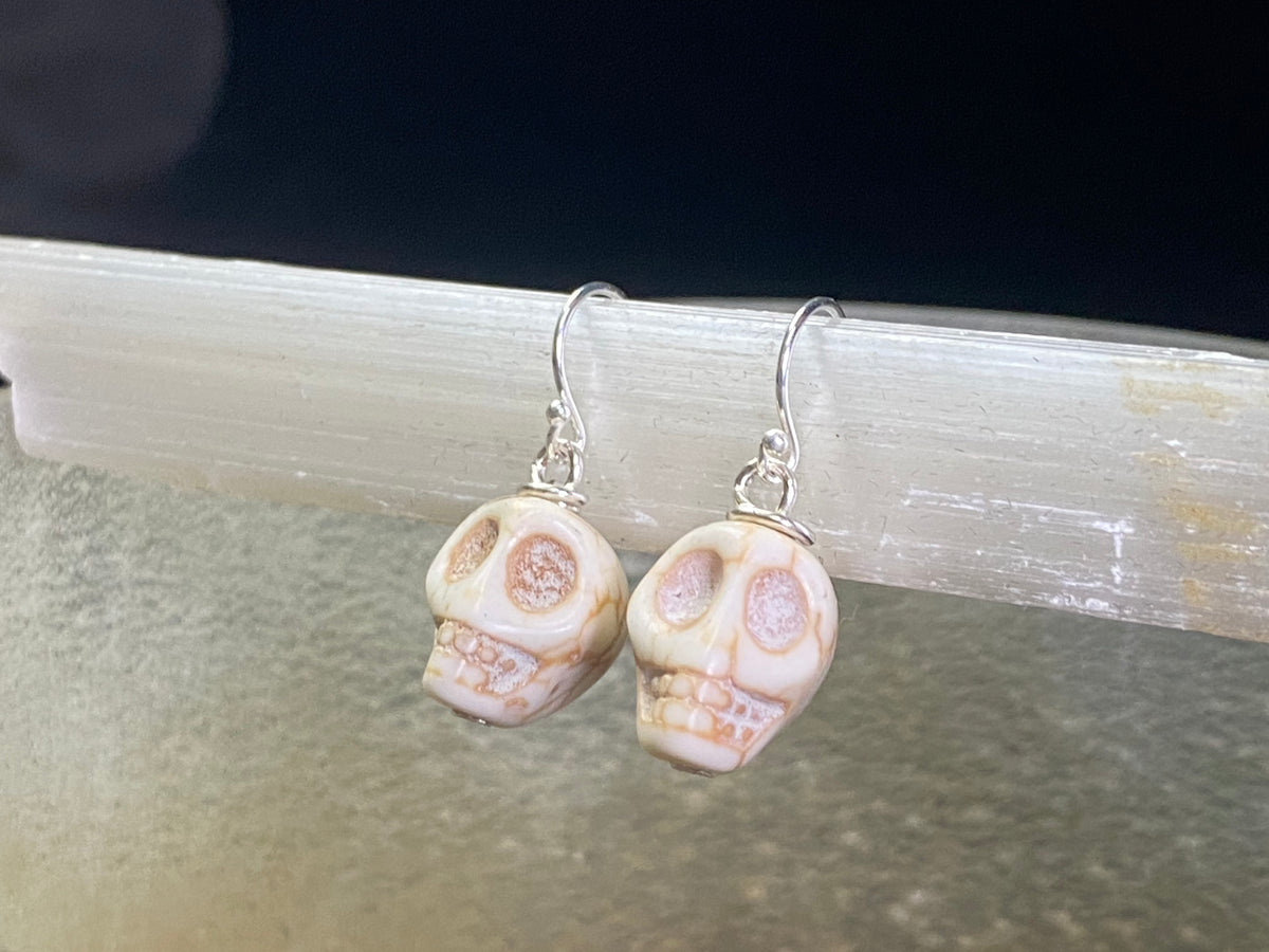 Hand carved from American howlite, these simple skull earrings feature sterling silver hooks.