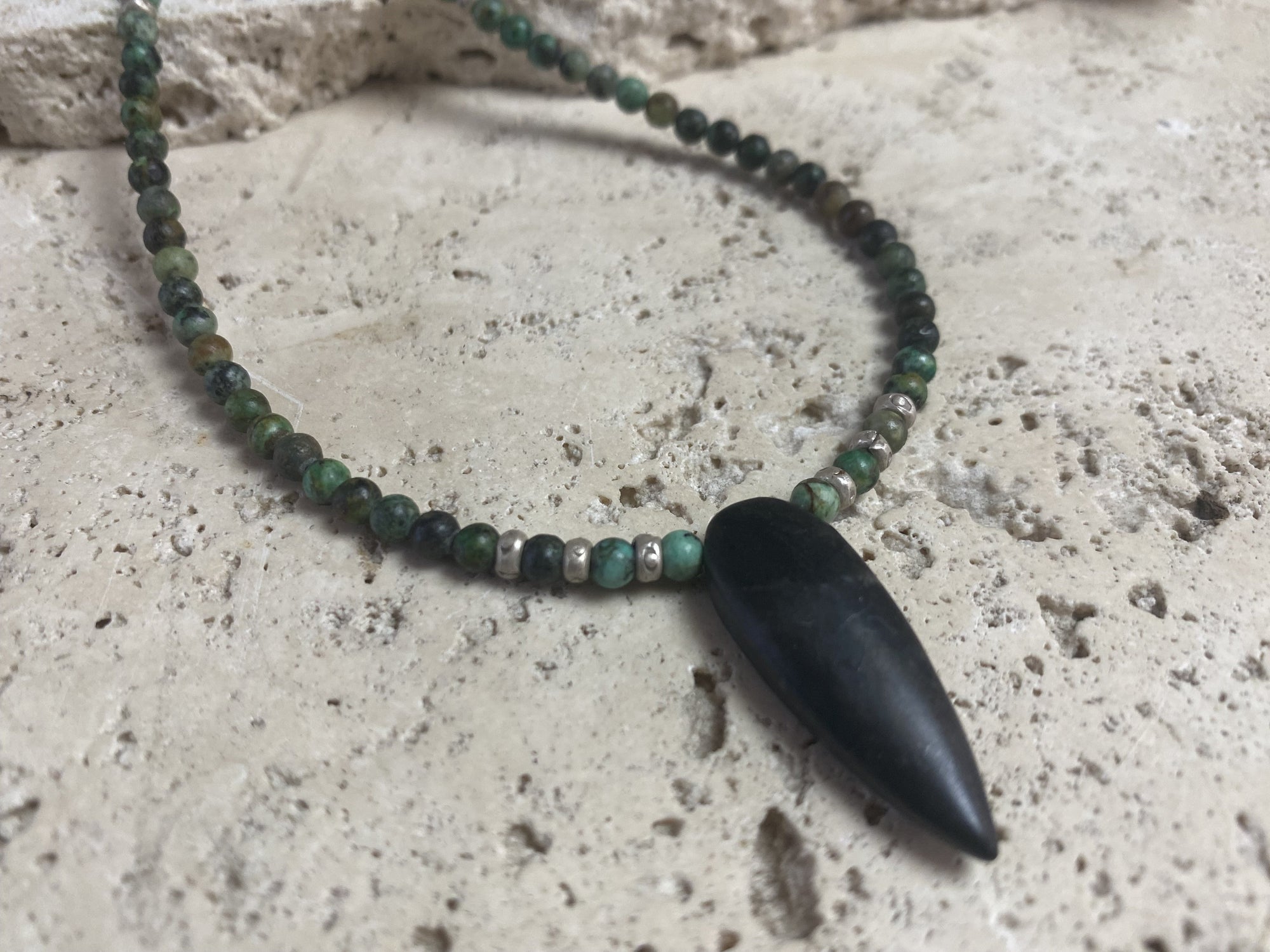 Fine unisex necklace of round natural stone beads, highlighted with Karen hill tribe sterling silver "eye beads" and a long pendant of unpolished onyx. The effect is simple and stunning. Finished with sterling silver findings and hook clasp. Length 42 cm