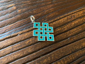 Sterling silver and turquoise Endless Knot pendant, one of the eight auspicious symbols of Buddhism. Sterling silver, set with ground chips of turquoise in enamel, from Nepal. Height 4 cm including bail
