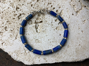 Lapis lazuli bracelet consists of hand cut tubes of dark blue natural matched,  graduated lapis tube beads. Finished with sterling silver ball spacer beads and a sterling silver clasp