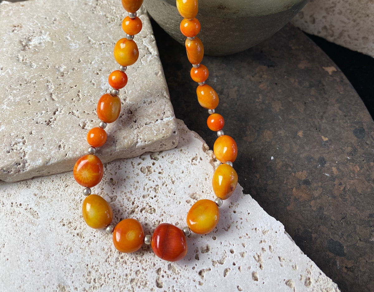 Bold coral necklace featuring orange red coral boulder beads of different sizes finished with sterling silver detailing