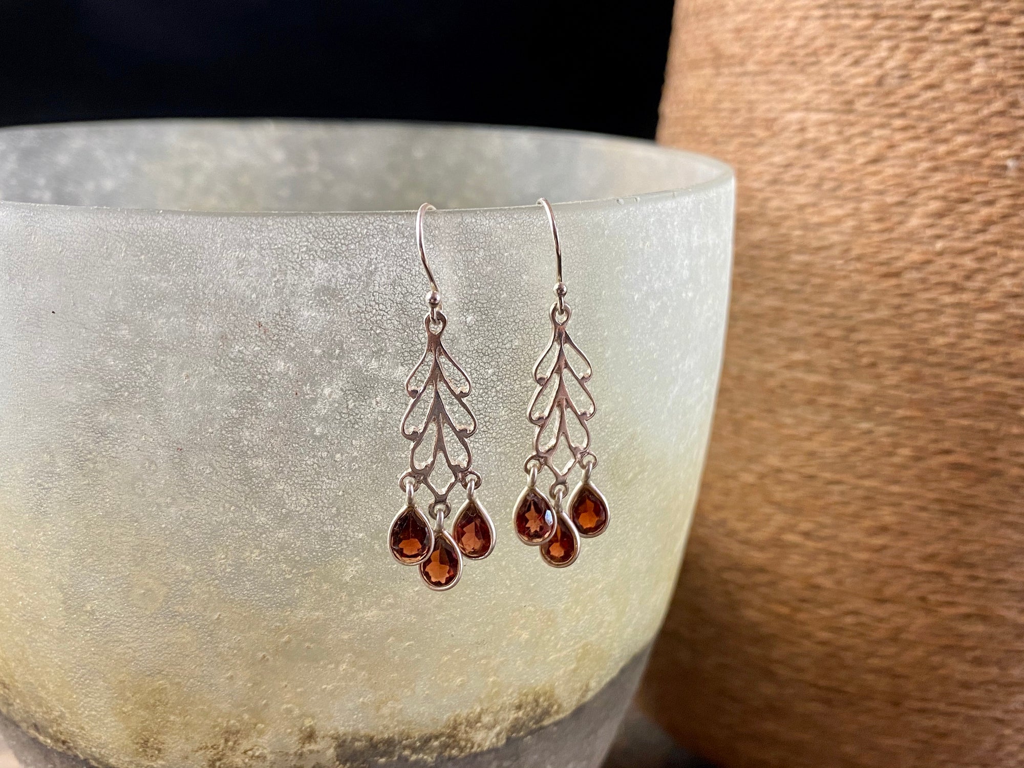 Garnet and silver earrings featuring a silver mount with three perfect facet cut teardrop garnets hanging en tremblant