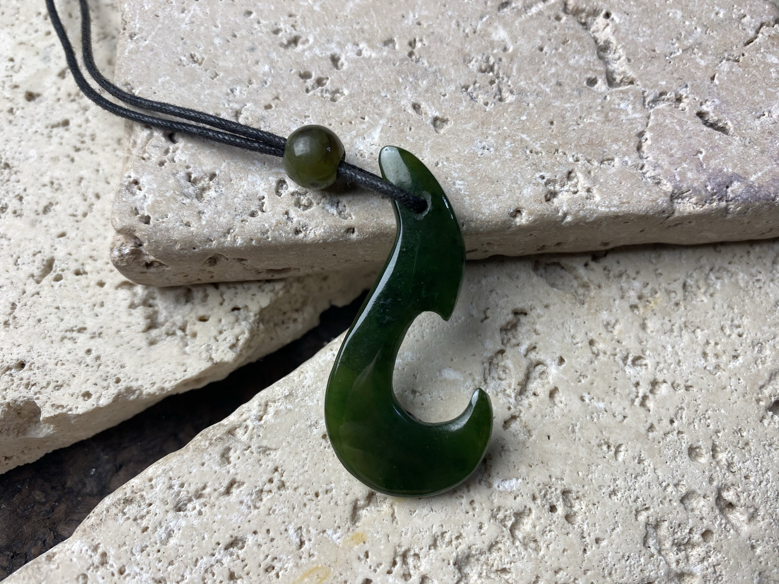 Natural green jade hei matau fish hook pendant, hand carved in New Zealand by a Maori craftsman.