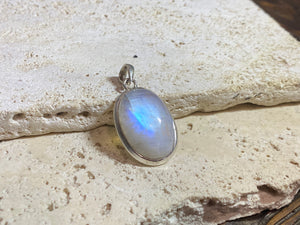 Oval high cut rainbow moonstone pendant set in sterling silver with a generous flexible bail to take a large chain or cord. A high quality stone with blue colour and fire. 