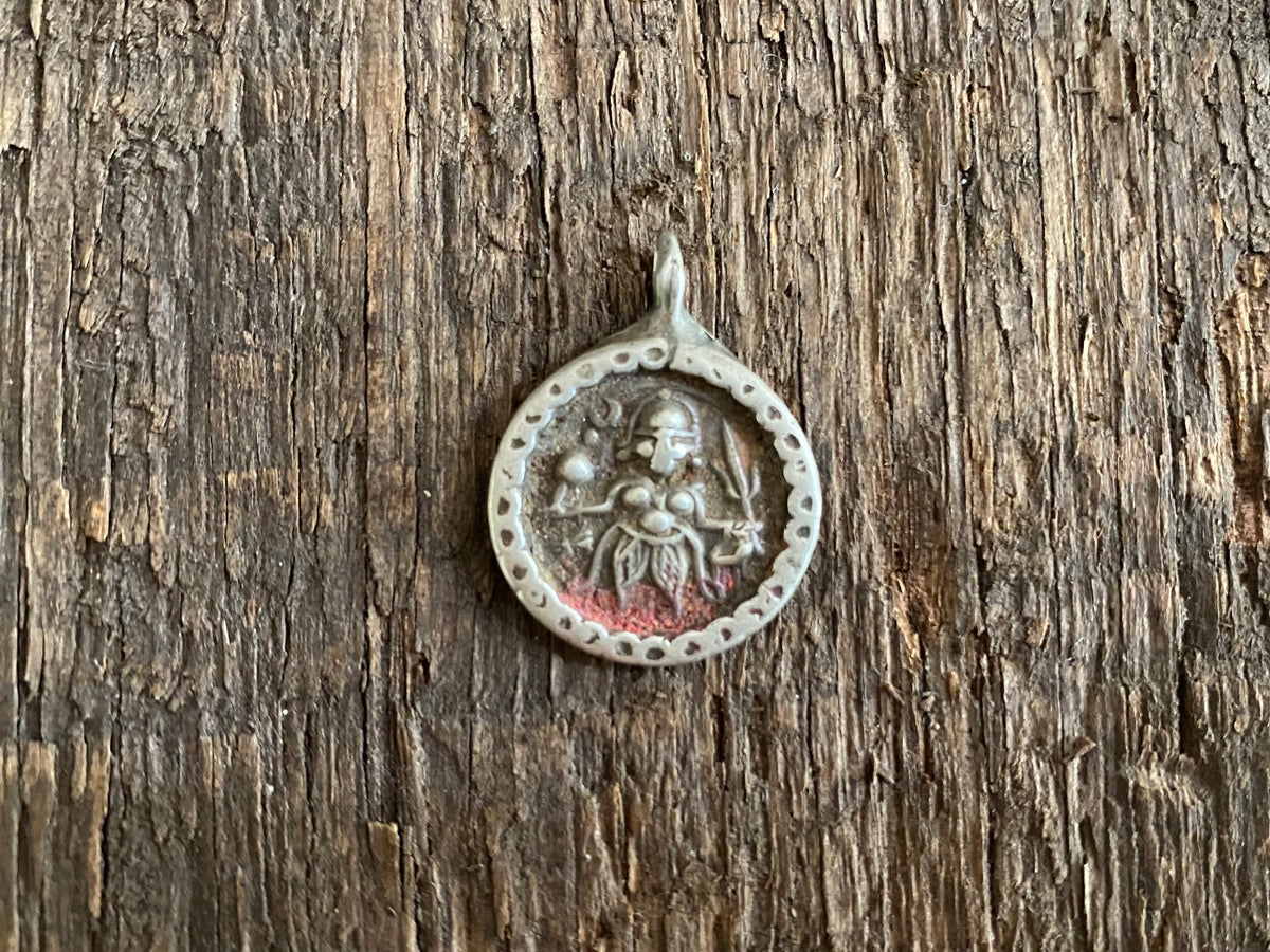 Antique silver amulets representing the Hindu god Kali, in her protective form, and dating from the early 19th - early 20th century.  Measurements: all vary between 1.5 and 2.2 cm in width