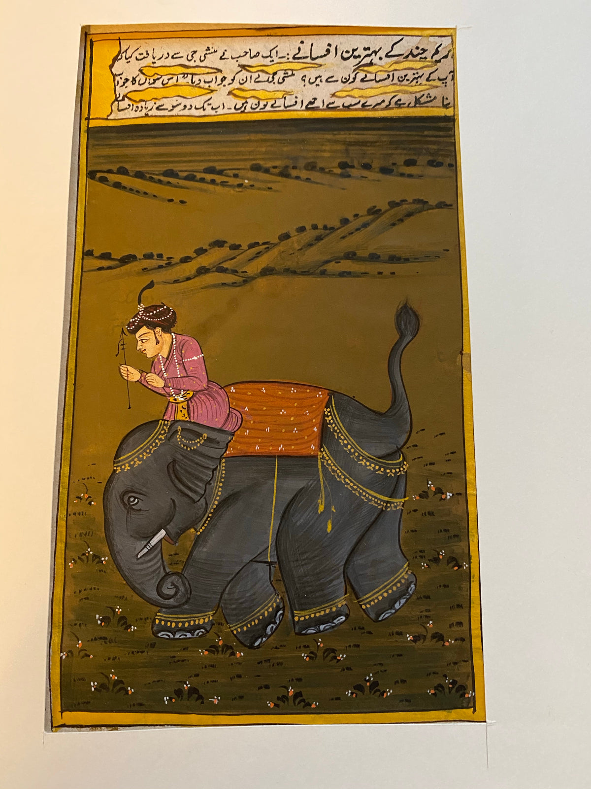 An original painting in the Mogul style, depicting a well-to-do young man on his way on elephant back to see his beloved