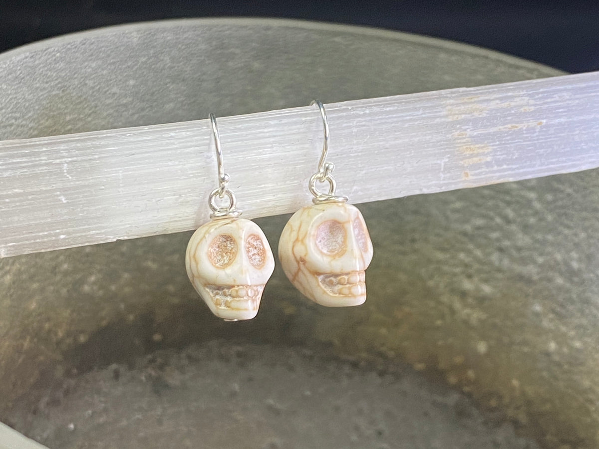 Hand carved from American howlite, these simple skull earrings feature sterling silver hooks.