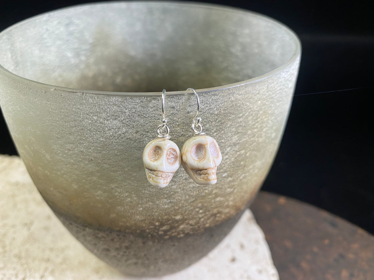 Hand carved from American howlite, these simple skull earrings feature sterling silver hooks.
